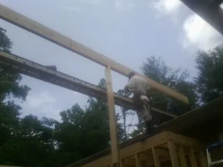 Carpenter setting a ridge beam over a new addition frame — Ice Dam Removal by Roofing Brothers in New Haven